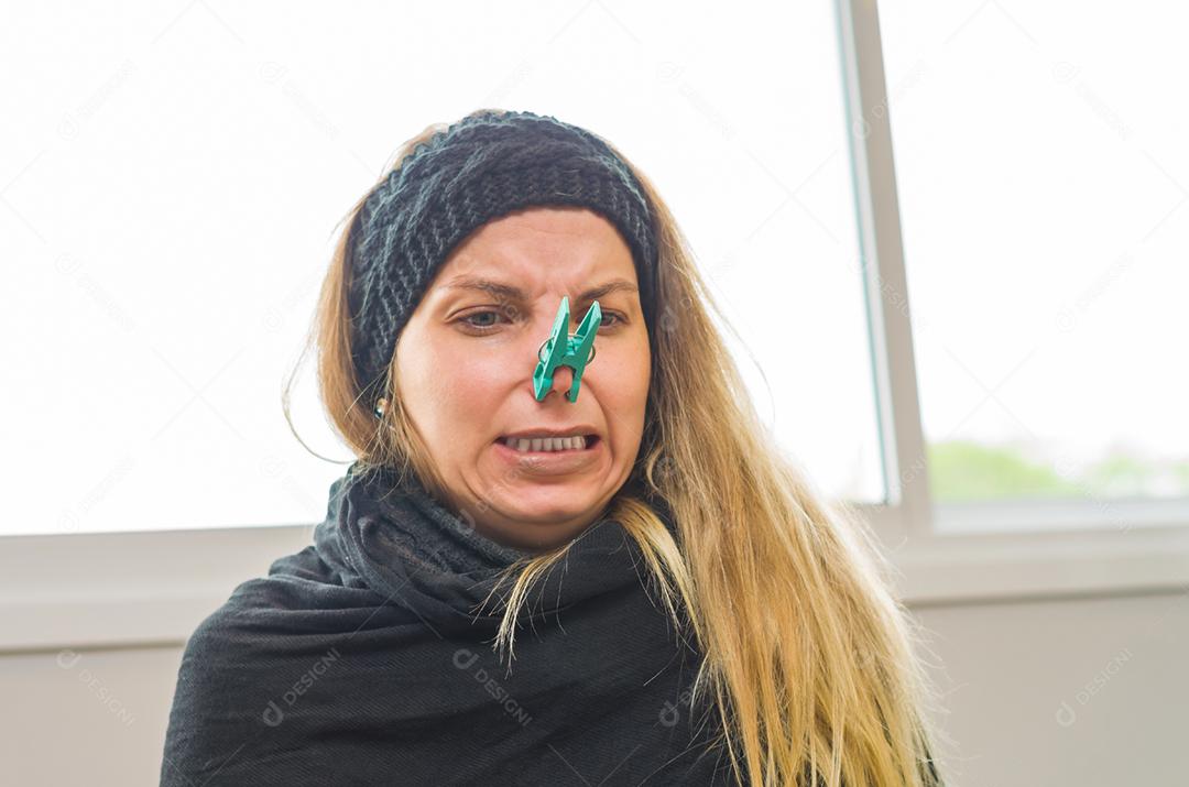 Grande conceito de alergia, rinite ao pólen. Jovem mulher loira com pega no nariz para plantar, flor.