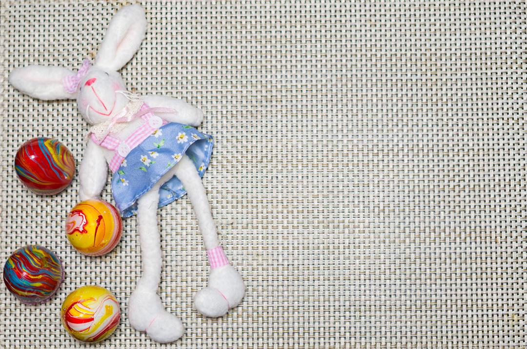 Conceito de Páscoa, coelhinho da Páscoa de pelúcia em fundo de palha com ovos decorados e coloridos.