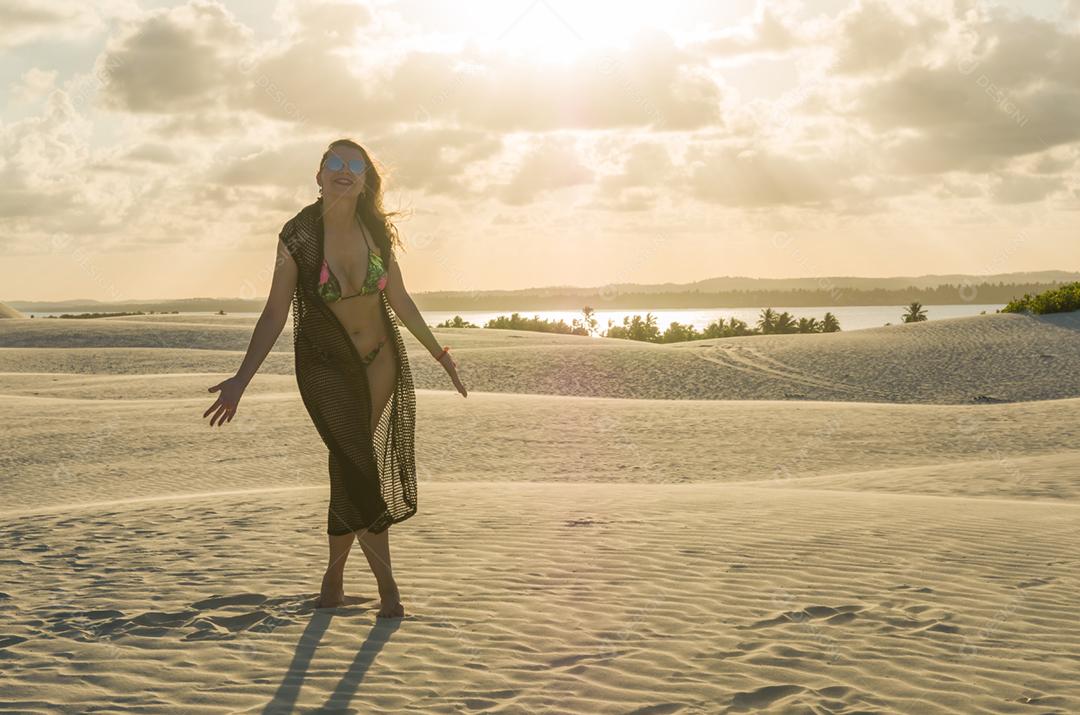 Jovem pousando nas dunas de areia da praia de Mangue Seco localizada na Bahia.