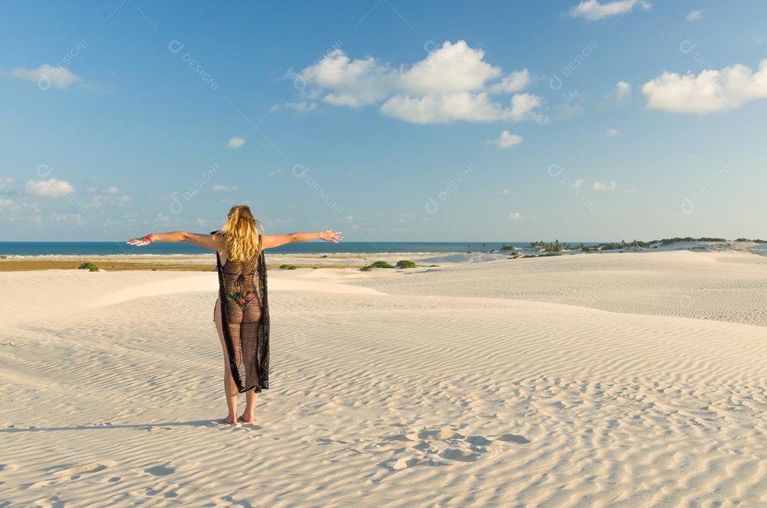 Jovem pousando nas dunas de areia da praia de Mangue Seco localizada na Bahia.