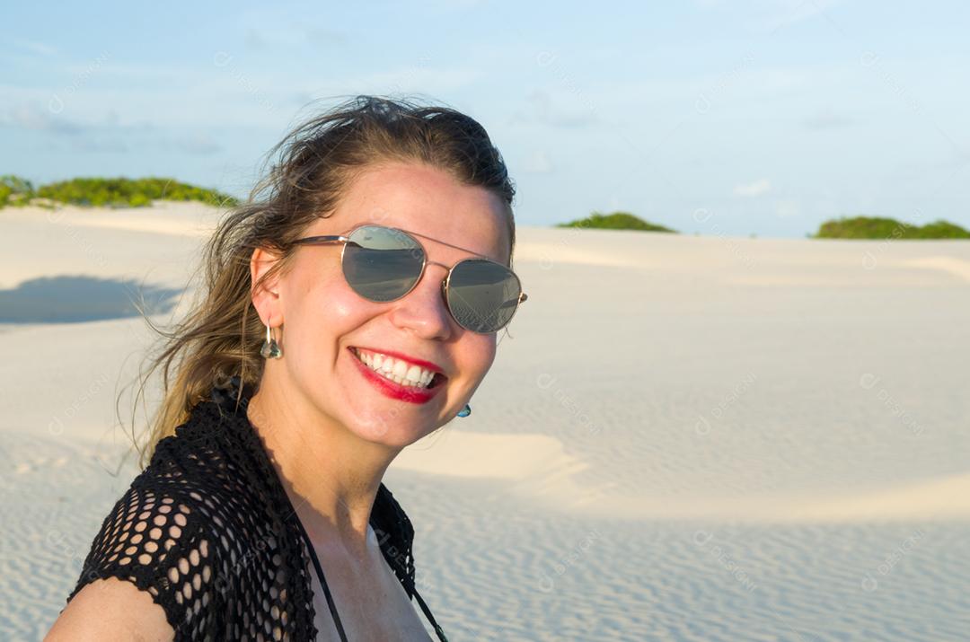 Jovem pousando nas dunas de areia da praia de Mangue Seco localizada na Bahia.