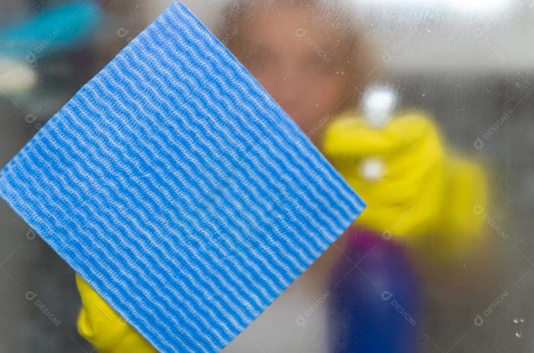 Grande conceito de limpeza doméstica, jovem loira limpando vidro do banheiro.