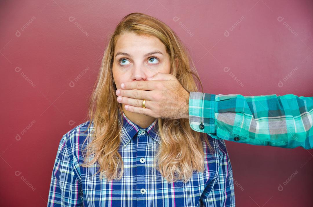 Grande conceito de censura masculina, mulher com a boca coberta pela mão do homem.
