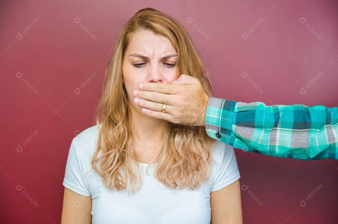 Grande conceito de censura masculina, mulher com a boca coberta pela mão do homem.
