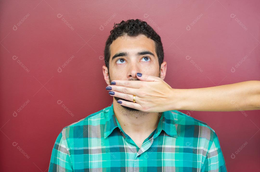 Grande conceito de censura feminina, homem com a boca coberta pela mão da mulher.