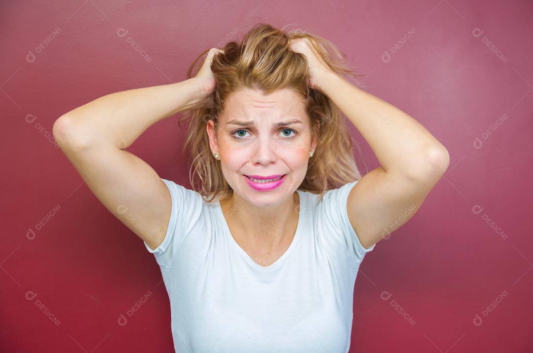 Conceito de preocupação, mulher com as duas mãos na cabeça sobre fundo vermelho.