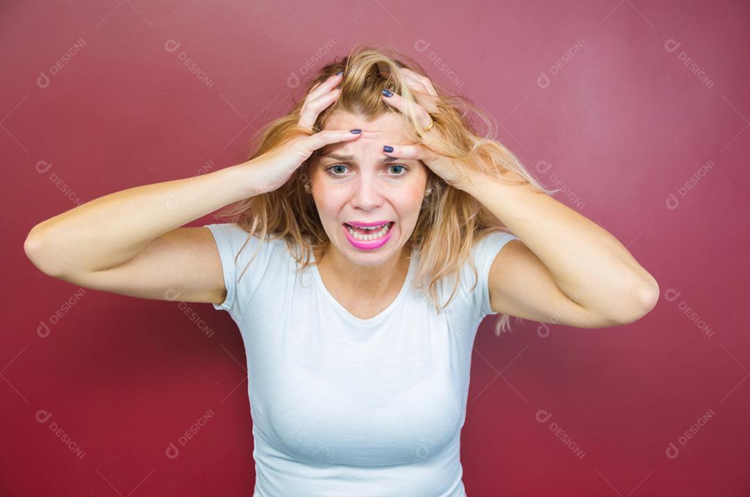 Conceito de preocupação, mulher com as duas mãos na cabeça sobre fundo vermelho.