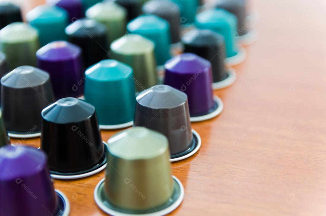 Cápsulas de café expresso coloridas, máquina de café, sobre fundo de madeira.