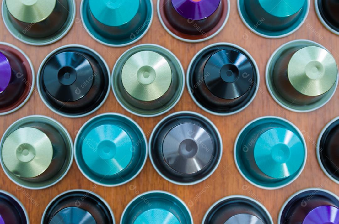 Cápsulas de café expresso coloridas, máquina de café, sobre fundo de madeira.