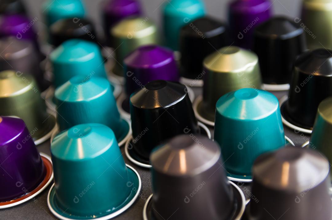 Cápsulas de café expresso coloridas, máquina de café, sobre fundo de madeira.