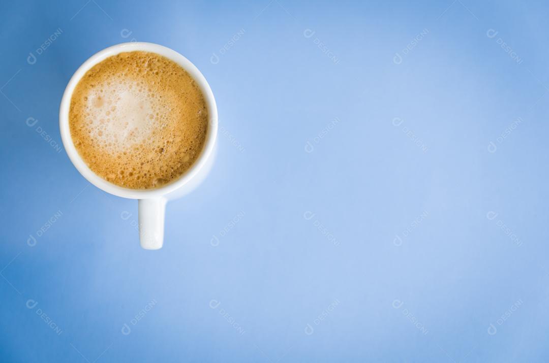 Xícara de café branca sobre fundo azul claro.