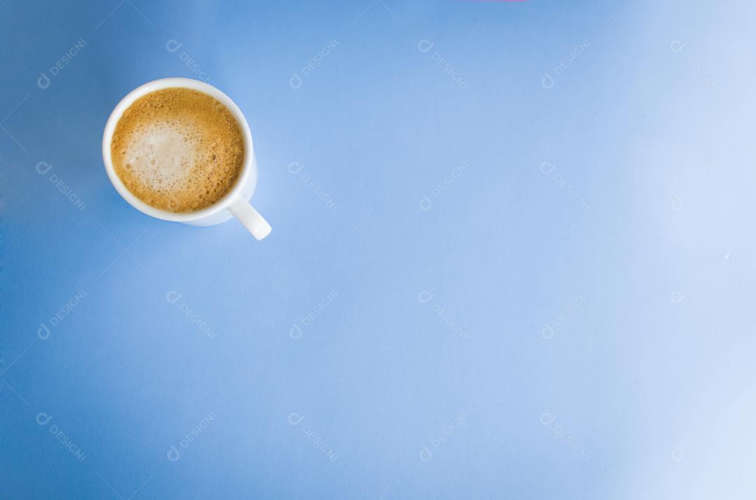 Xícara de café branca sobre fundo azul claro.