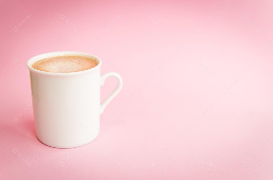 Xícara de café branca sobre fundo rosa claro.