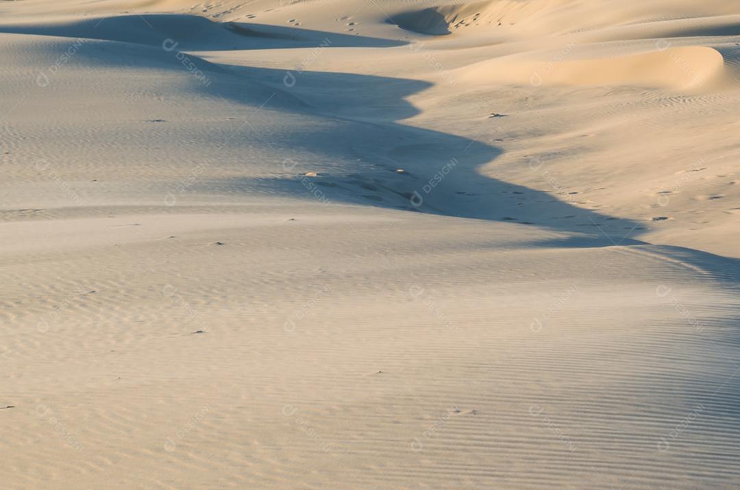 Hora dourada de dunas de areia, sol dourado batendo na areia.