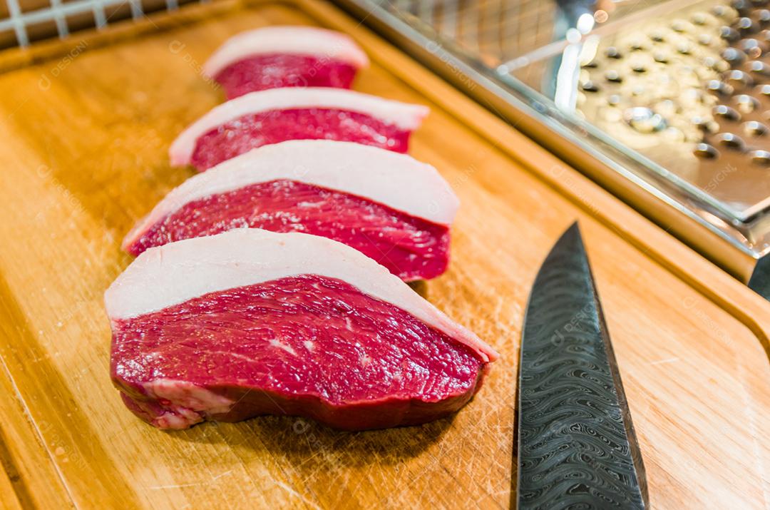 Linda foto de cortes de Picanha em uma tábua de madeira e uma linda faca de aço damasco personalizada