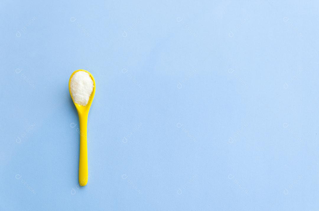 Colher com açúcar close-up em um fundo azul claro