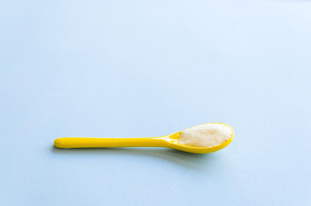 Colher com açúcar close-up em um fundo azul claro