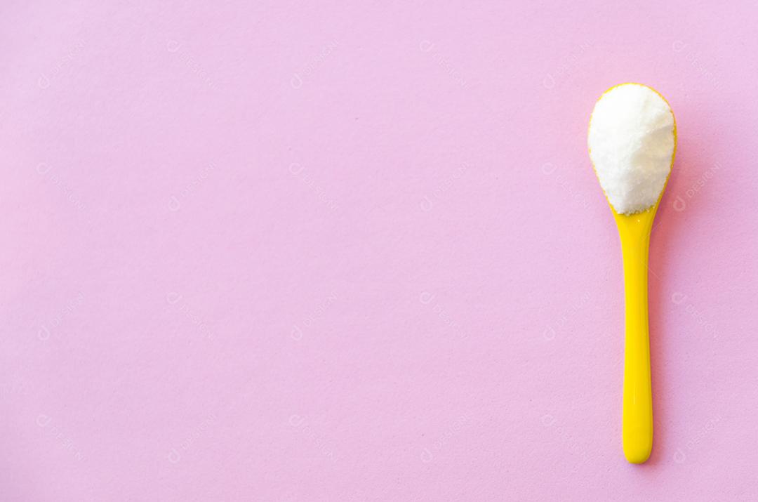 Colher com açúcar close-up em um fundo rosa