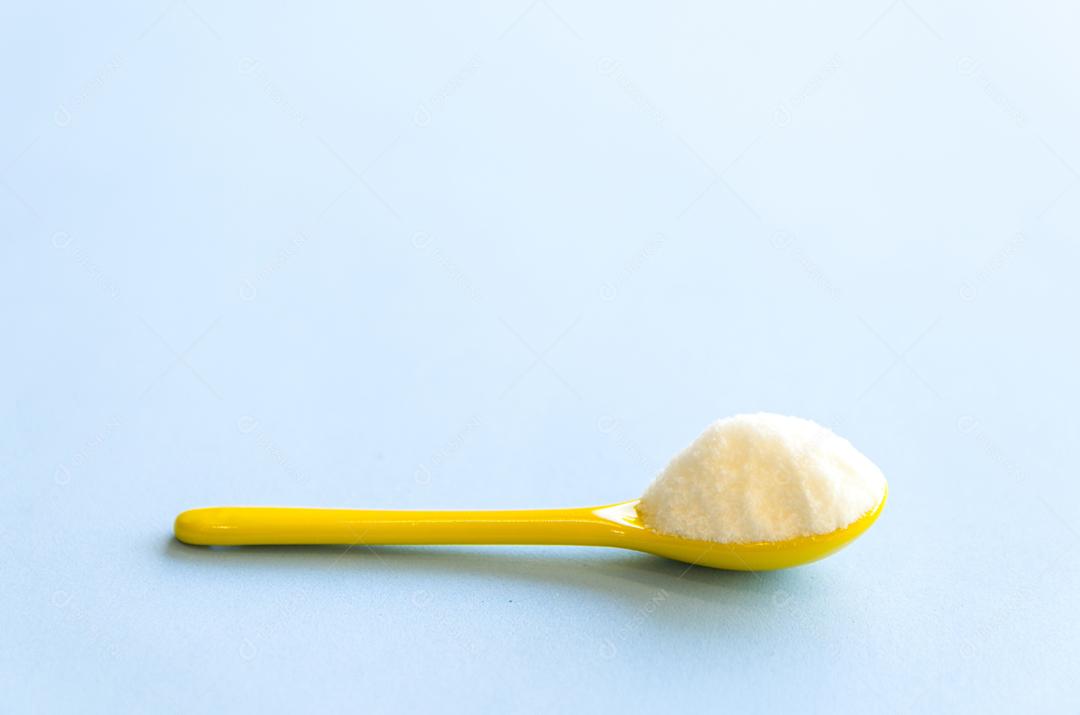 Colher com açúcar close-up em um fundo azul claro