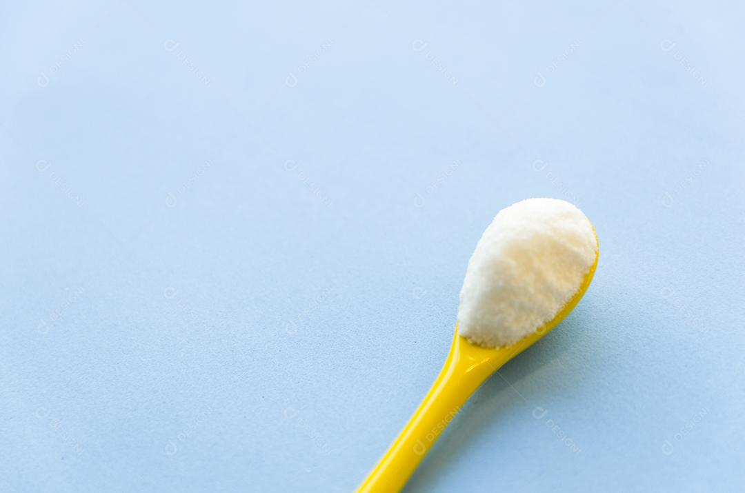 Colher com açúcar close-up em um fundo azul claro