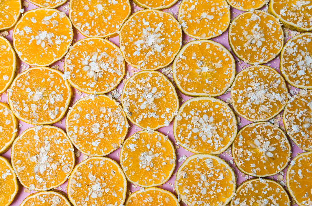 Linda textura de laranja fatiada com flocos de aveia no fundo rosa