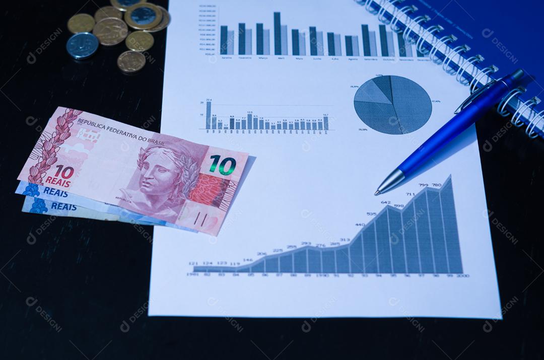 Computador portátil, caneta, gráficos, cartão de crédito e dinheiro brasileiro