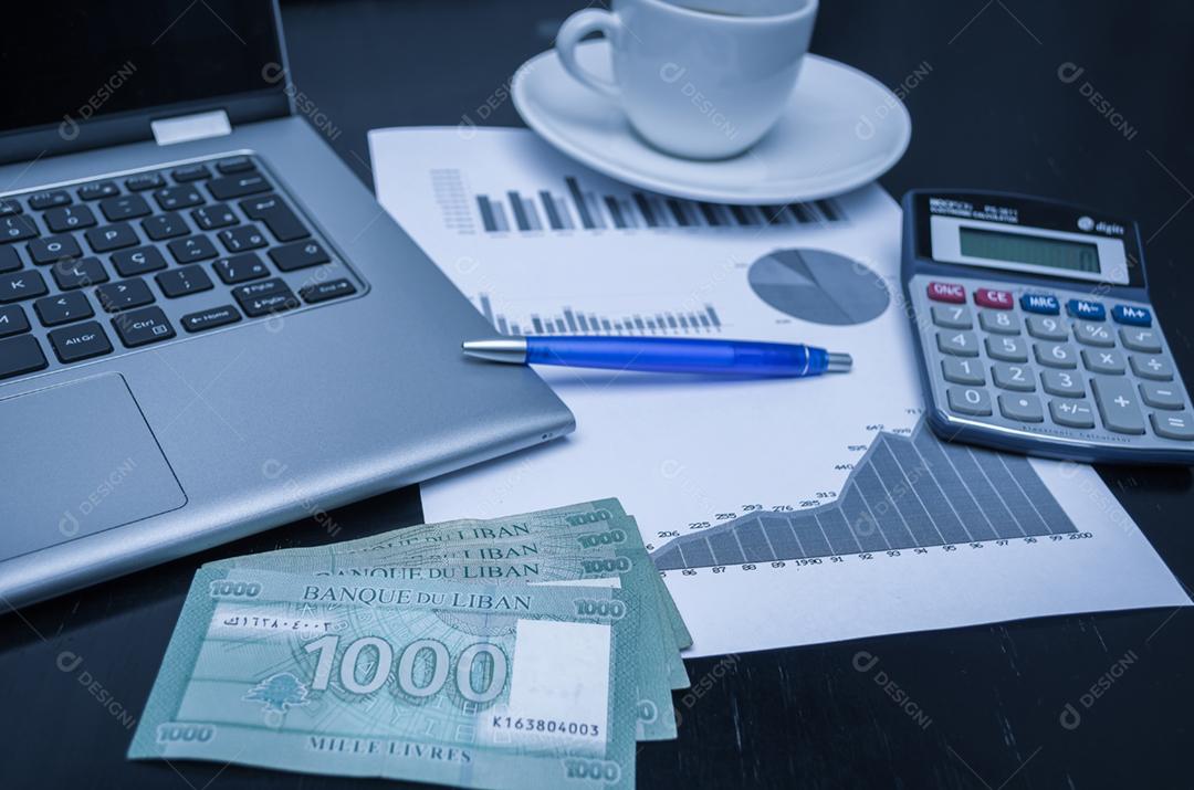 Laptop, xícara de café, caneta, calculadora, gráficos e dinheiro Libra libanesa, conceito de finanças