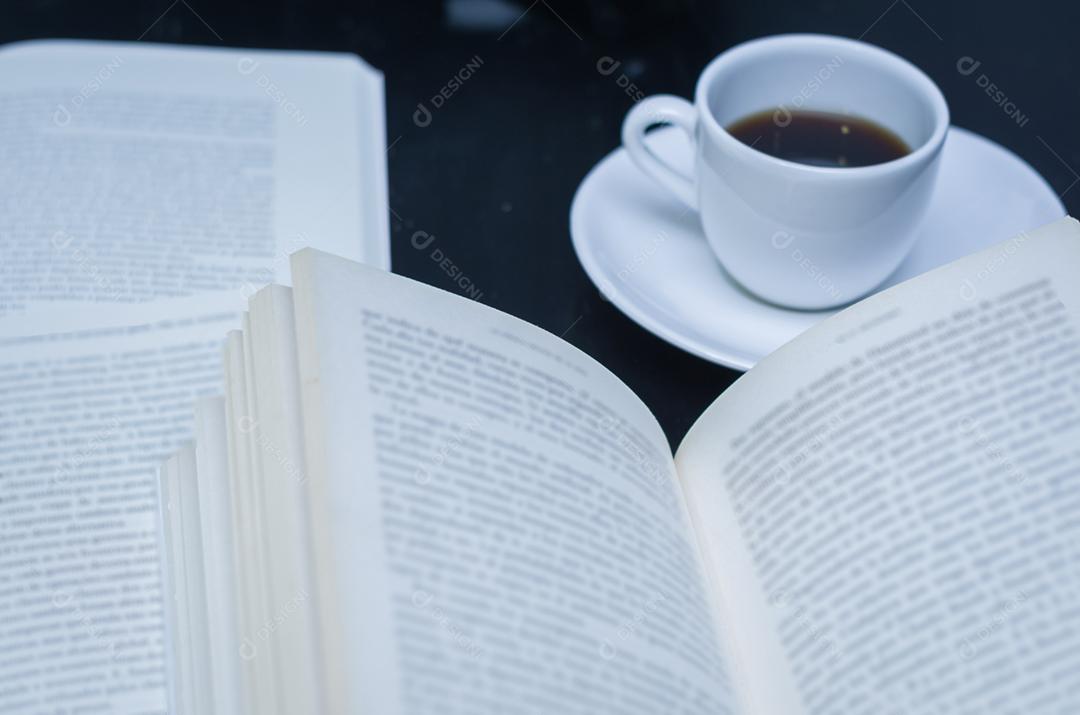 Lendo um livro e tomando café desfocado.