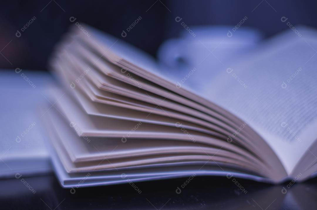 Lendo um livro e tomando café desfocado.