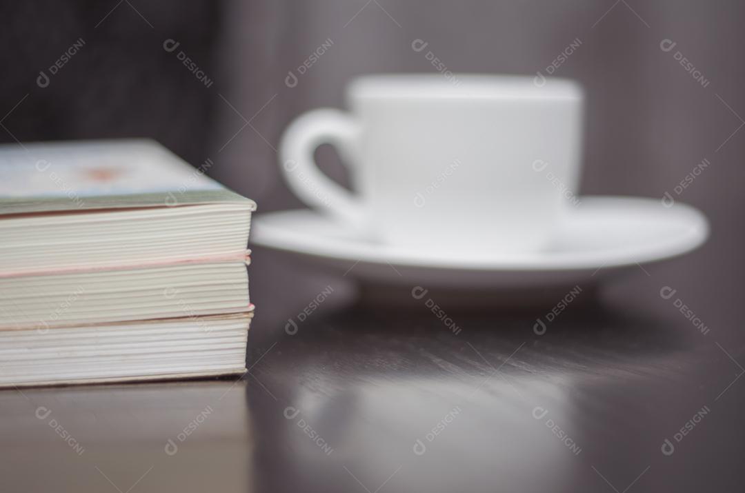 Lendo um livro e tomando café desfocado.