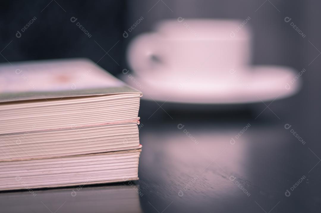 Lendo um livro e tomando café desfocado.