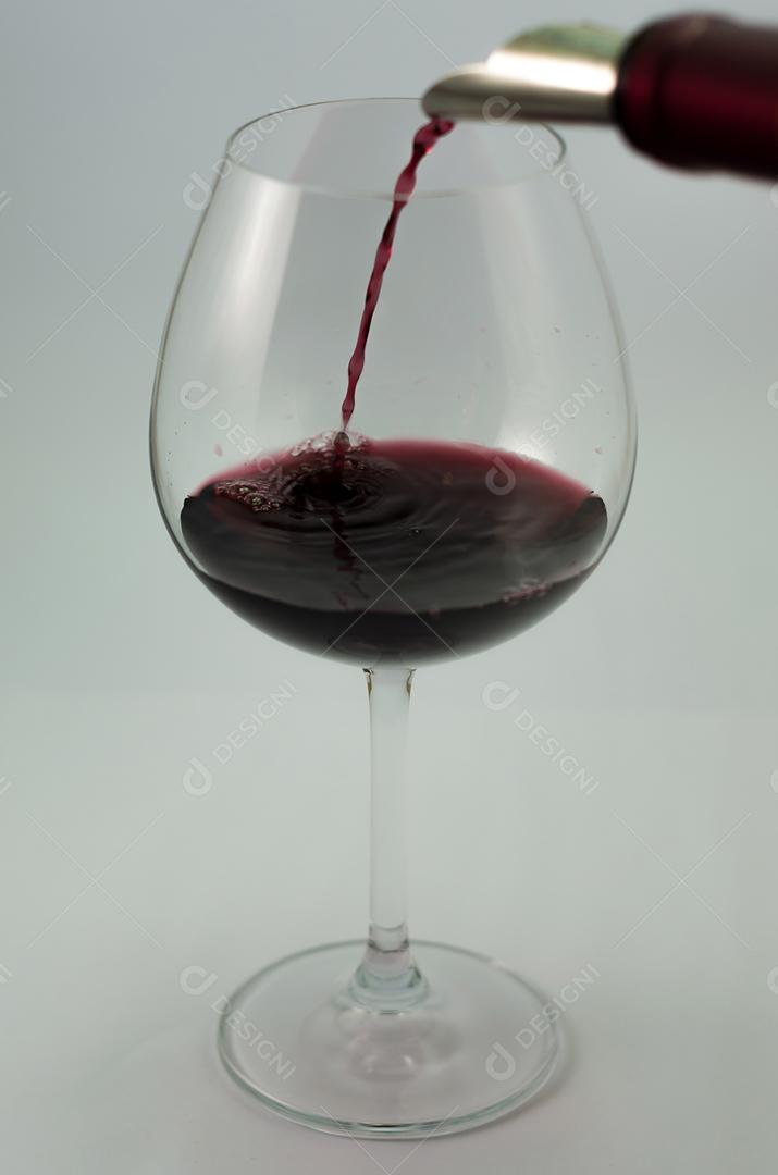 Grande copo de vinho sendo servido com vinho tinto