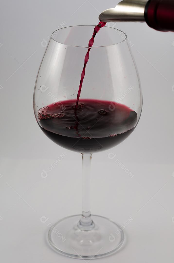 Grande copo de vinho sendo servido com vinho tinto