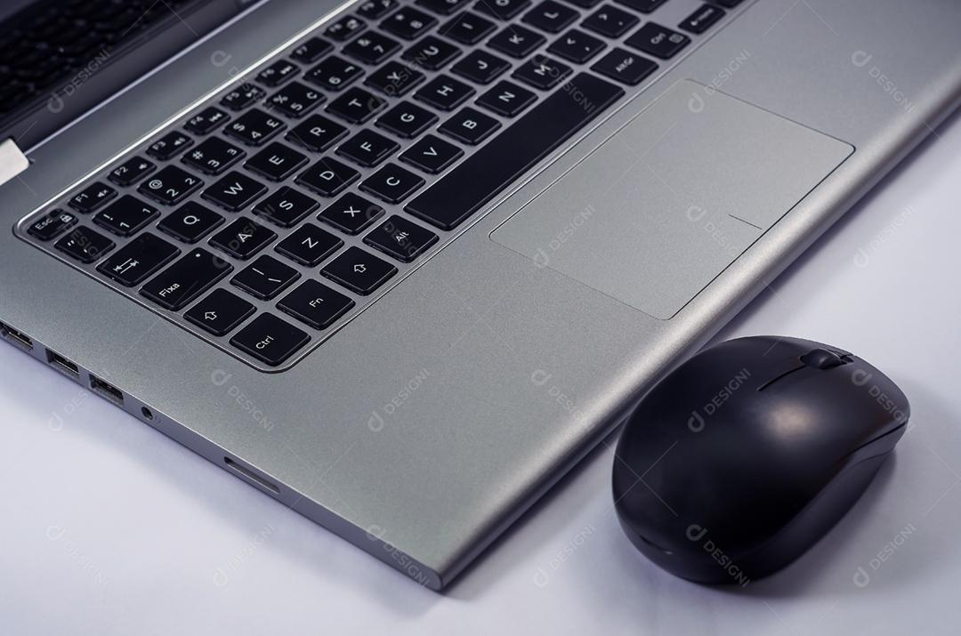 Laptop e mouse em um ângulo sobre fundo branco.