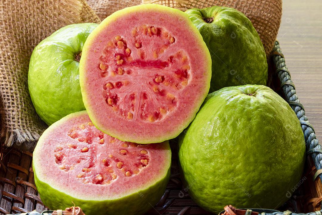 goiaba vermelha fatiada com folha verde em madeira rústica