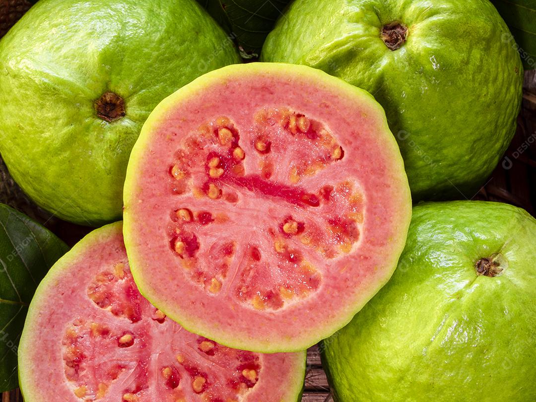 goiaba vermelha fatiada com folha verde em madeira rústica