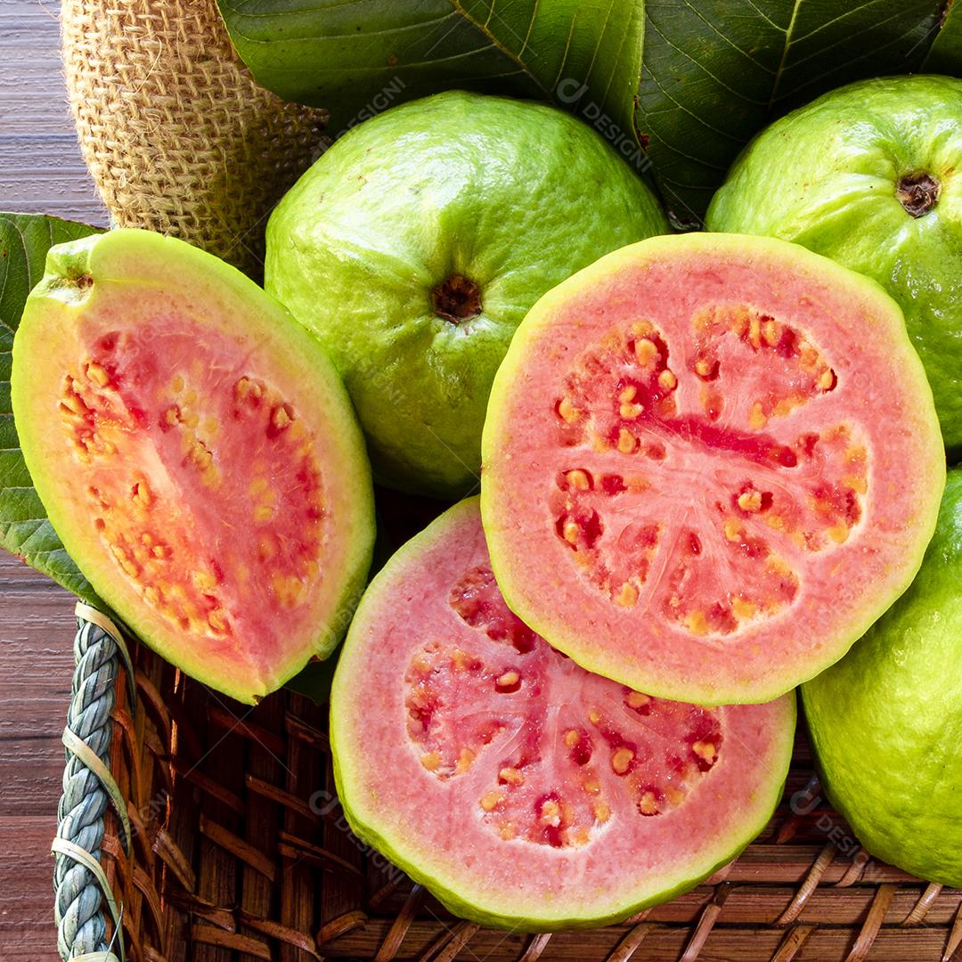 Bela cesta de madeira com goiaba vermelha e algumas folhas verdes