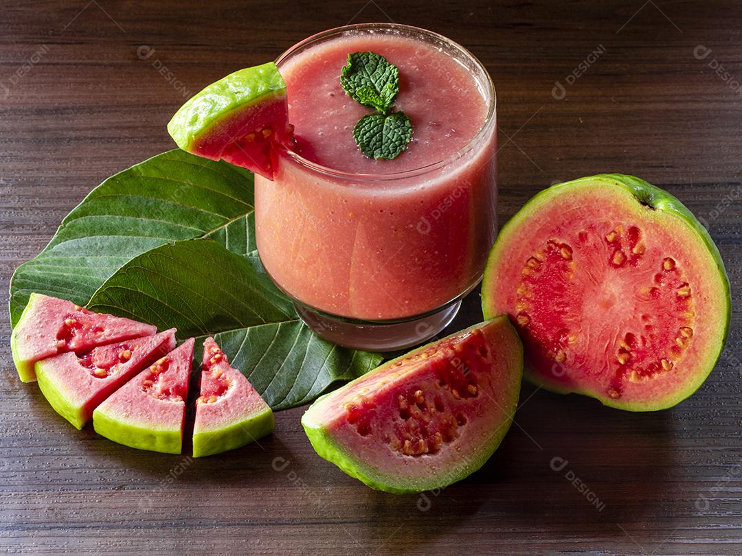 Delicioso suco de goiaba vermelha ao lado de uma fatia de goiaba