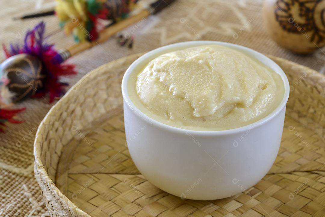 Sorvete cupuacu, fruta da Amazônia brasileira, em uma tigela branca sobre uma mesa com artesanato amazônico desfocado ao fundo.