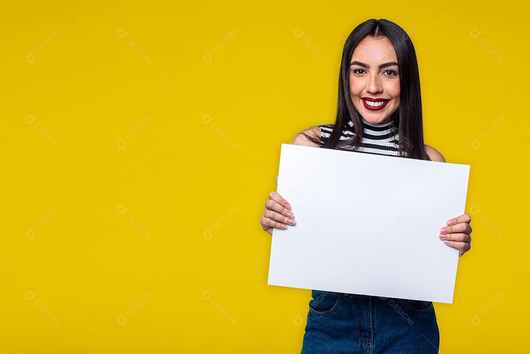 Mulher segurando placa branca, isolada em fundo amarelo para texto.