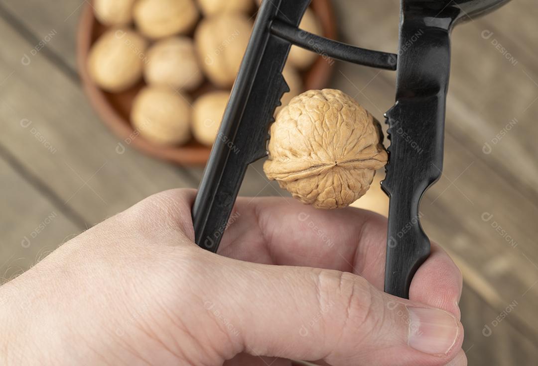 Mão quebrando nozes desfocadas no fundo