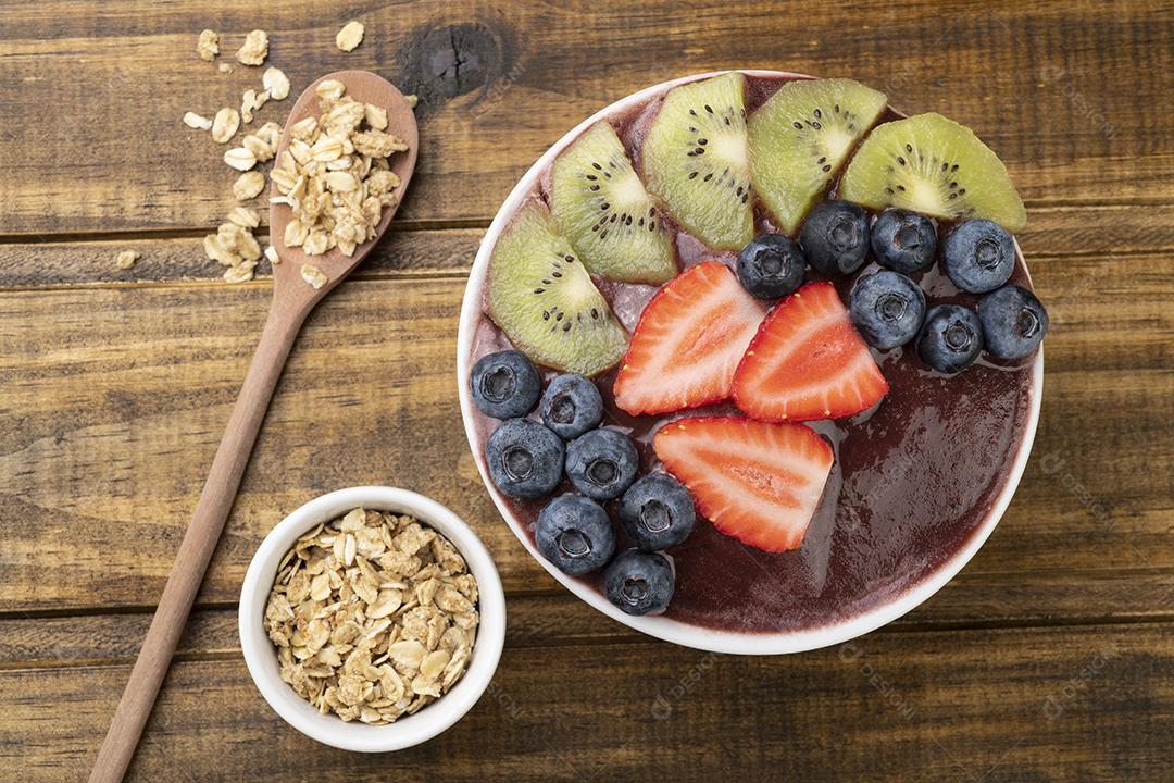 Tigela típica de açaí brasileira com frutas e granola sobre madeira