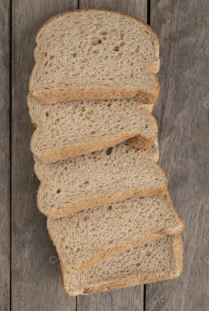 Fatias de pão de trigo inteiro sobre mesa de madeira