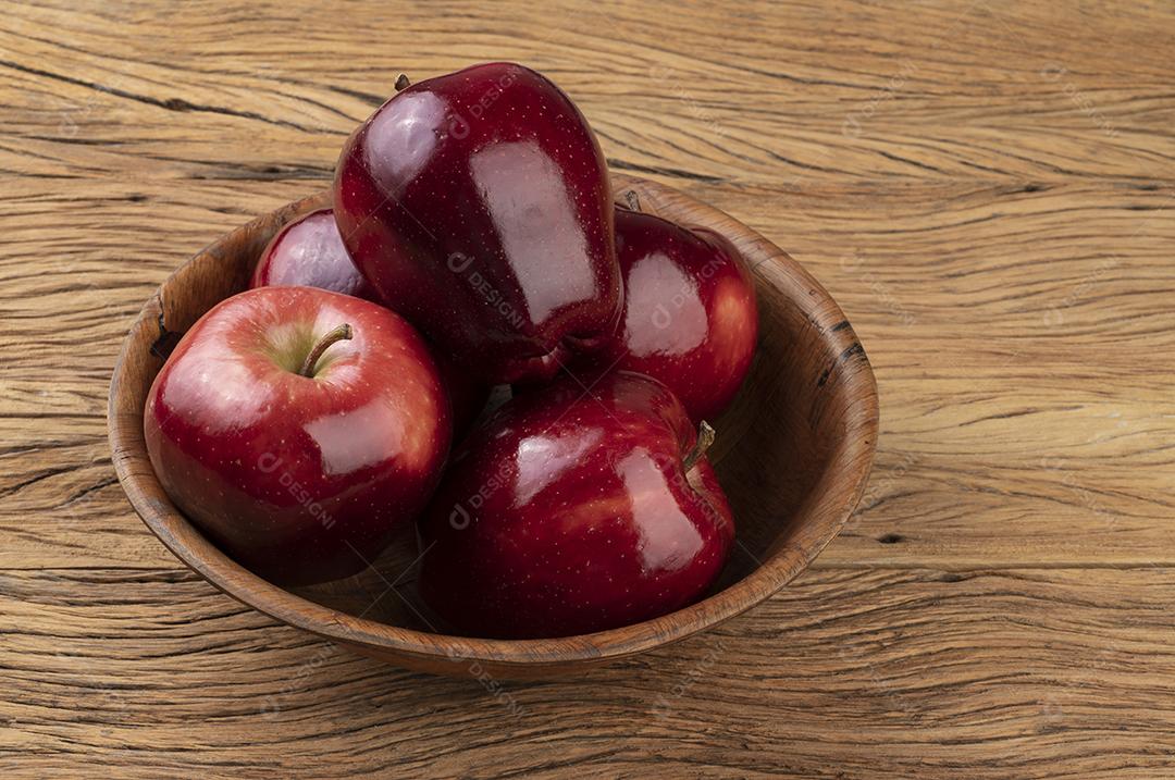 Maçãs vermelhas em uma tigela sobre mesa de madeira
