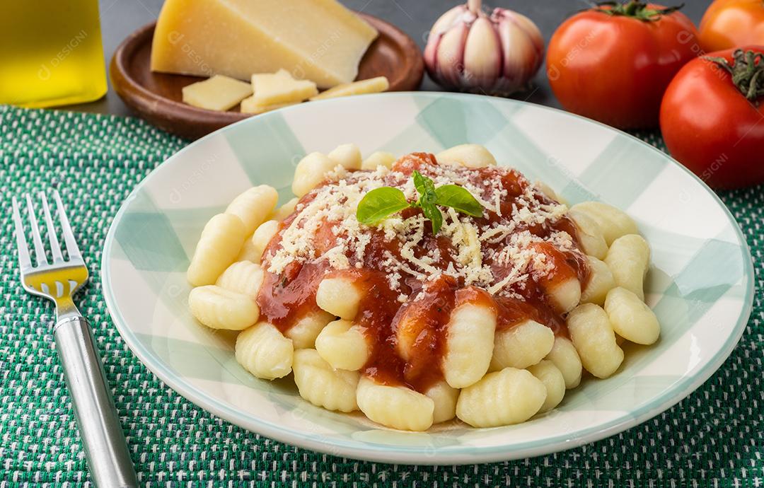 Nhoque de massa italiana em um prato com molho de tomate, manjericão e queijo parmesão.