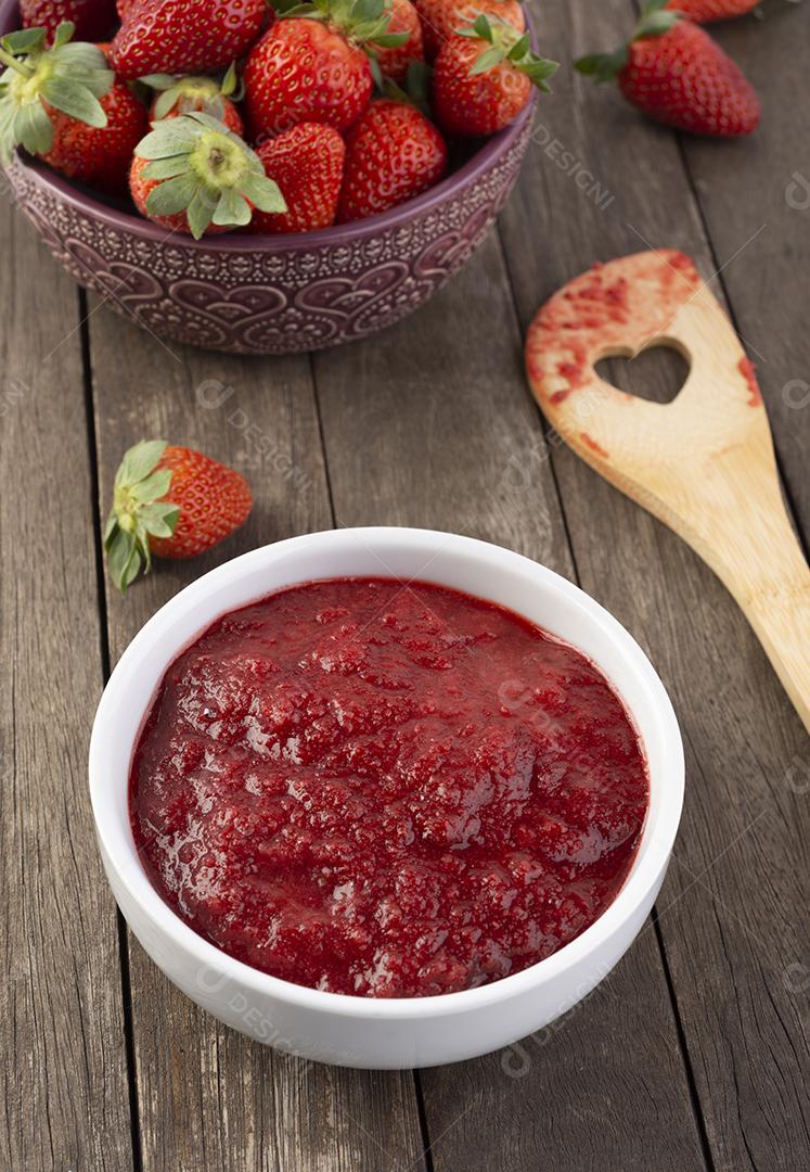 Tigelas com morangos, geleia de morango e colher de pau