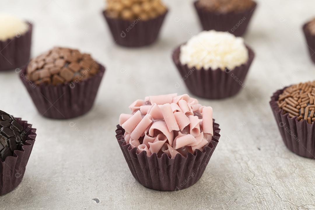 Brigadeiros típicos brasileiros, vários sabores sobre fundo de concreto.