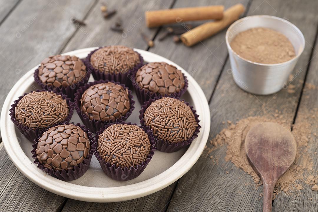 Brigadeiros típicos brasileiros, vários sabores sobre mesa de madeira.