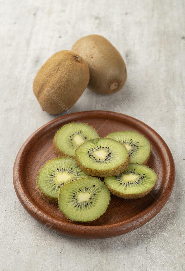 Dois kiwis com fatias em uma tábua de madeira