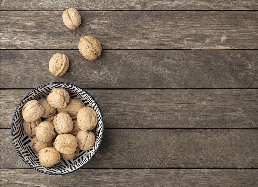 Nozes sobre uma mesa de madeira e em uma tigela